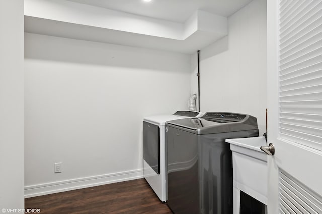 washroom with dark wood-type flooring, laundry area, baseboards, and washing machine and clothes dryer