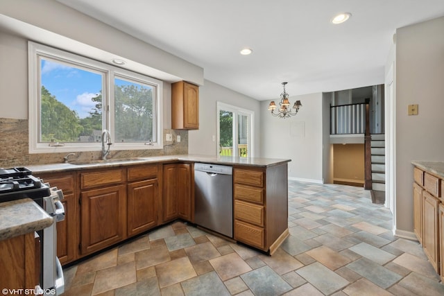 kitchen with stainless steel appliances, brown cabinets, a sink, and a peninsula