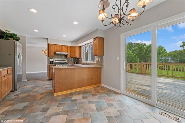 kitchen with tasteful backsplash, visible vents, stainless steel appliances, under cabinet range hood, and a chandelier