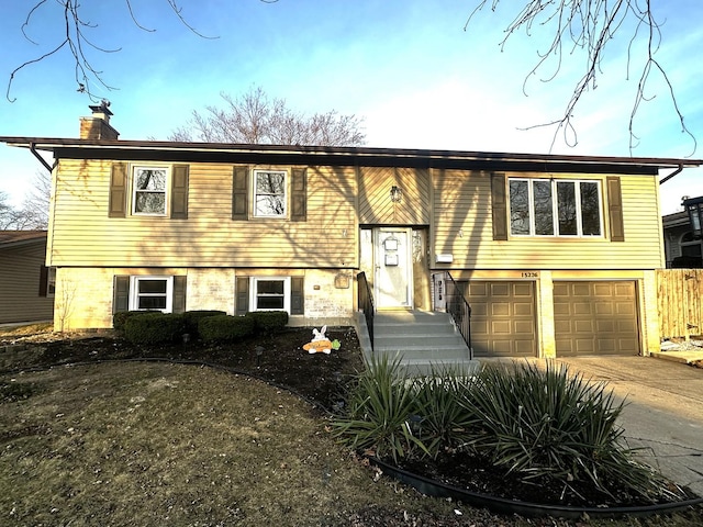 split foyer home featuring a garage, driveway, and a chimney