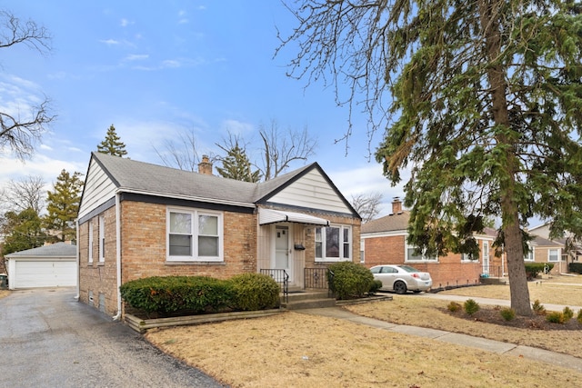 bungalow-style home featuring a garage, brick siding, an outdoor structure, and a chimney