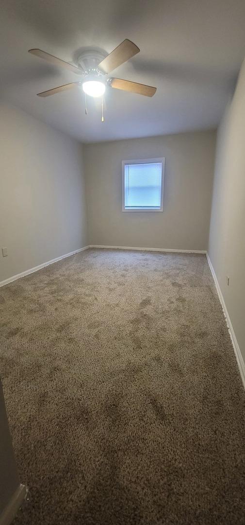 spare room featuring ceiling fan, carpet flooring, and baseboards