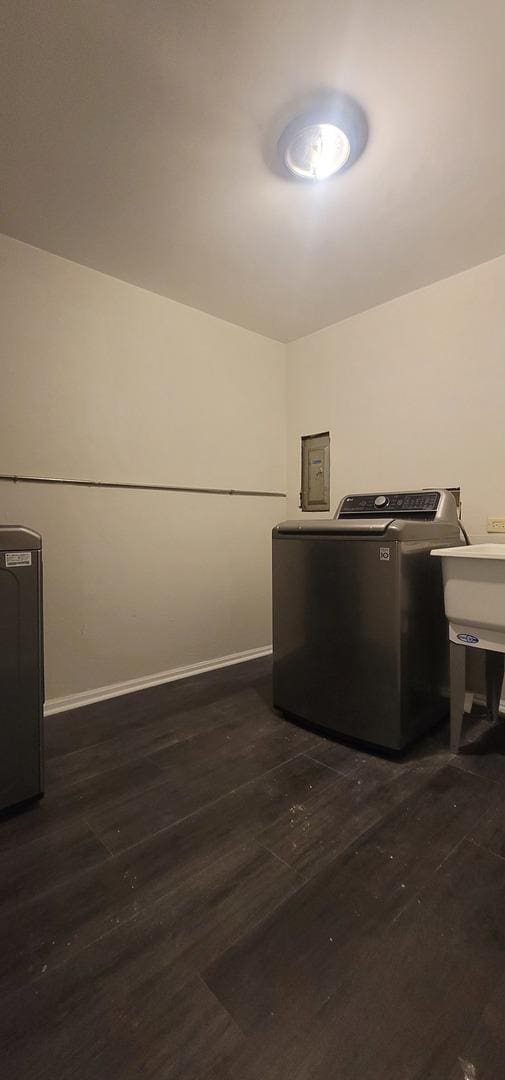 interior space with washing machine and dryer, laundry area, dark wood-type flooring, a sink, and baseboards