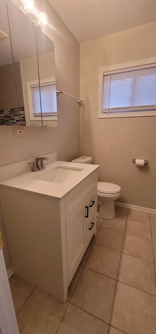 bathroom featuring tile patterned flooring, baseboards, vanity, and toilet