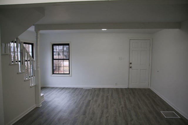 unfurnished room featuring beam ceiling, dark wood finished floors, visible vents, stairway, and baseboards