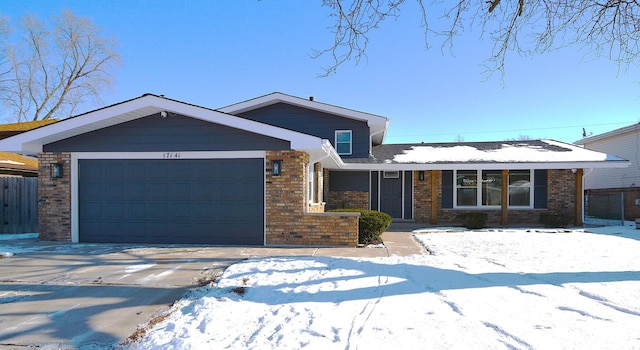 view of front of home featuring an attached garage, fence, concrete driveway, and brick siding