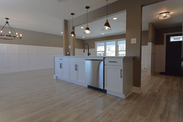 kitchen featuring light wood-style flooring, white cabinets, dishwasher, and decorative light fixtures