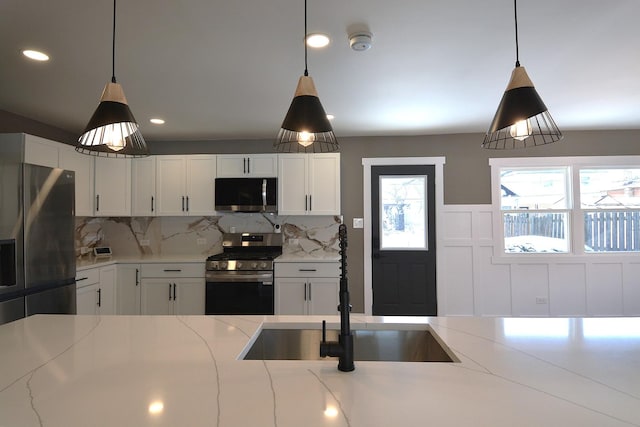 kitchen with white cabinetry, tasteful backsplash, appliances with stainless steel finishes, and light stone counters