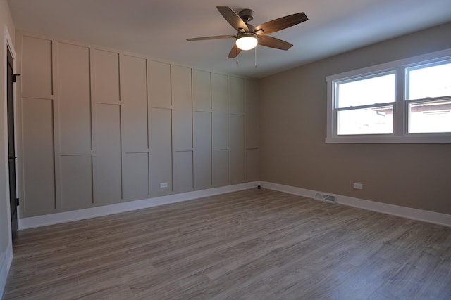 unfurnished room with visible vents, ceiling fan, baseboards, and wood finished floors