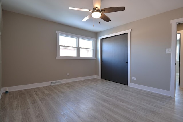 unfurnished bedroom featuring a ceiling fan, baseboards, visible vents, light wood-style floors, and a closet