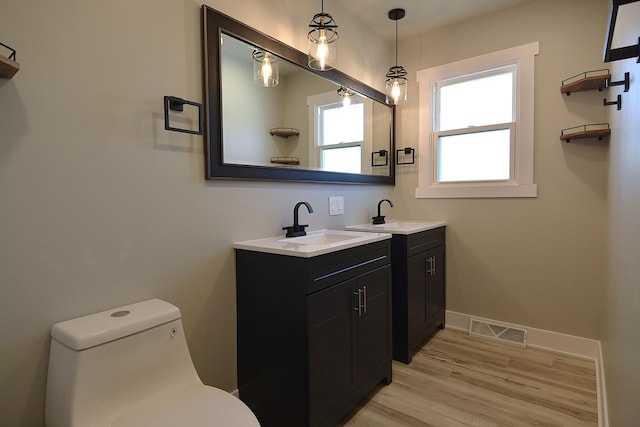 bathroom featuring visible vents, two vanities, a sink, and wood finished floors