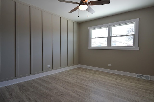 empty room featuring ceiling fan, light wood-style flooring, visible vents, and baseboards