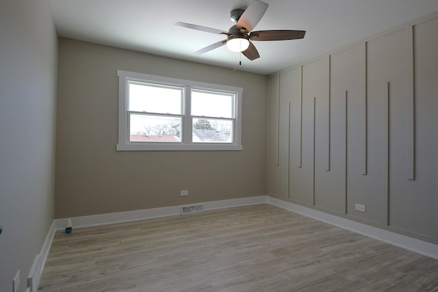 empty room featuring light wood-style flooring, visible vents, ceiling fan, and baseboards