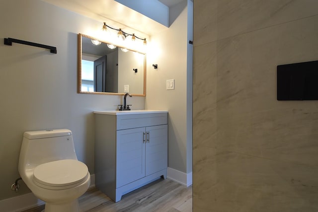 bathroom with baseboards, vanity, toilet, and wood finished floors