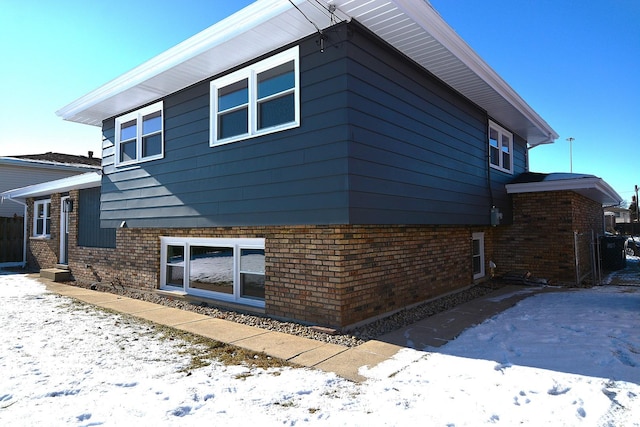 snow covered property with brick siding