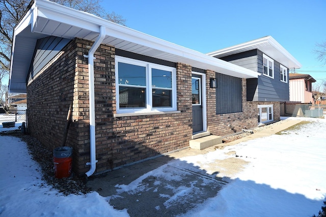 tri-level home featuring entry steps, brick siding, and fence