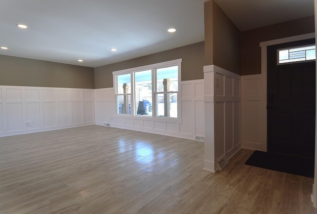 foyer entrance with visible vents, a wainscoted wall, light wood-type flooring, a decorative wall, and recessed lighting