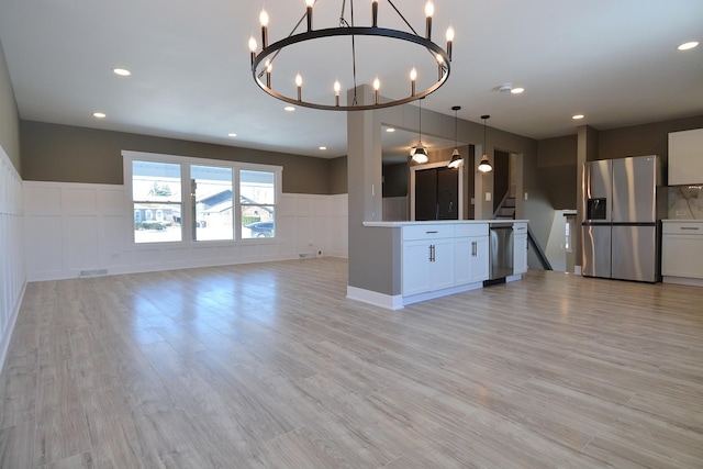 kitchen with light wood-type flooring, a decorative wall, stainless steel appliances, and open floor plan