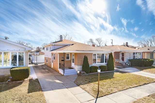 view of front of home featuring driveway, brick siding, a chimney, and a shingled roof