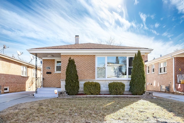 bungalow-style home featuring a chimney, a front lawn, and brick siding