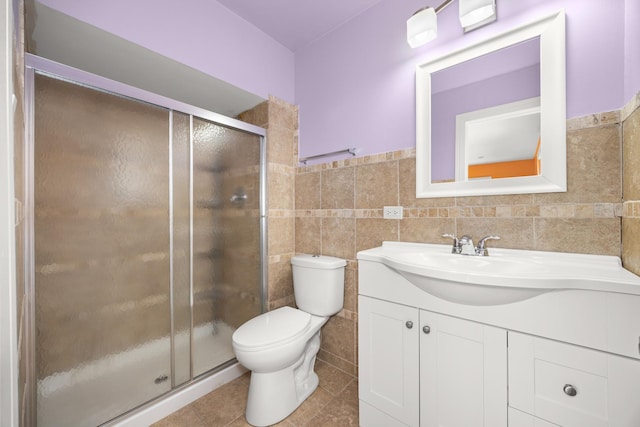 full bath with a stall shower, toilet, tile patterned floors, vanity, and tile walls