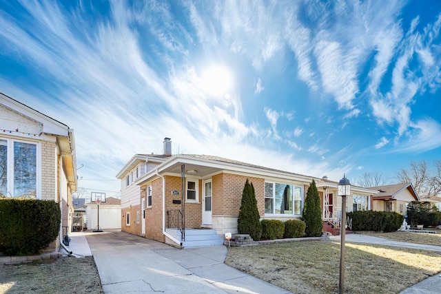 single story home with driveway, brick siding, a front lawn, and an outdoor structure