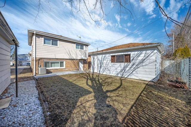 rear view of property with central air condition unit, a yard, an outbuilding, and brick siding