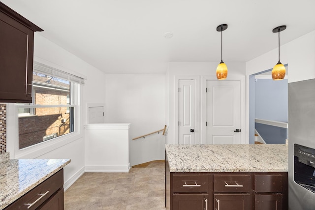 kitchen featuring decorative light fixtures, dark brown cabinetry, baseboards, and light stone countertops