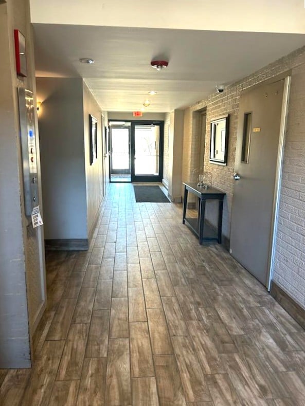 hallway with dark wood-style floors and brick wall