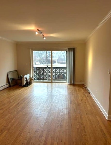 unfurnished living room with wood finished floors, baseboards, and ornamental molding