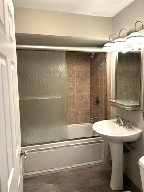 bathroom featuring enclosed tub / shower combo and toilet