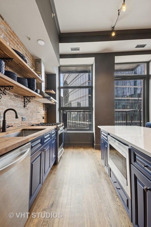 kitchen featuring stainless steel appliances, light countertops, visible vents, light wood-style flooring, and a sink