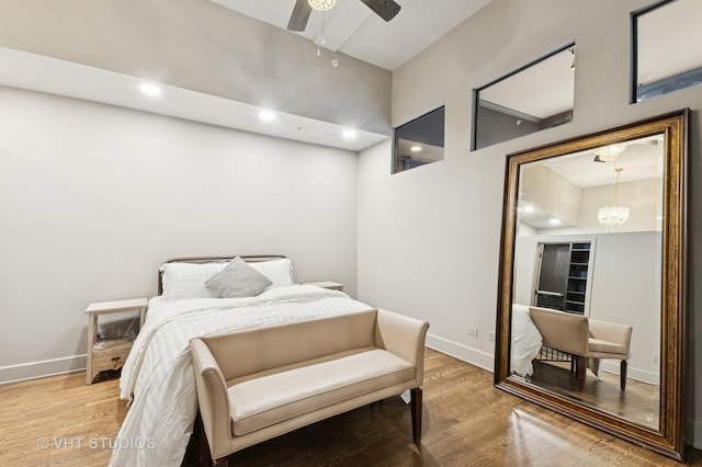 bedroom featuring ceiling fan with notable chandelier, recessed lighting, light wood-type flooring, and baseboards