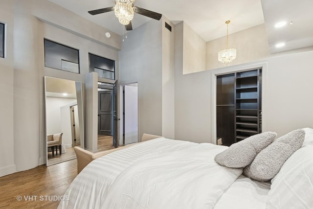 bedroom featuring visible vents, wood finished floors, an inviting chandelier, a high ceiling, and a closet