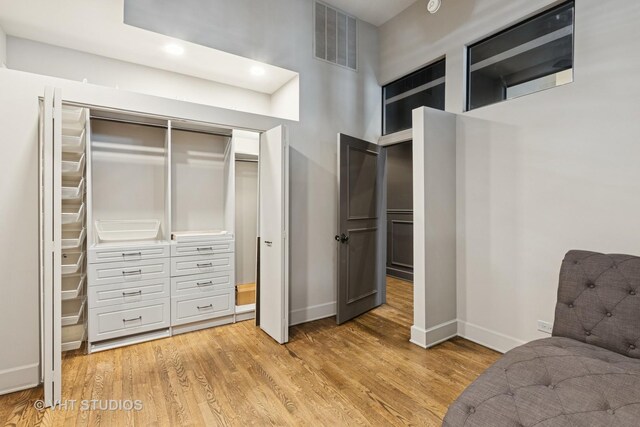 interior space with baseboards, a towering ceiling, visible vents, and light wood-style floors