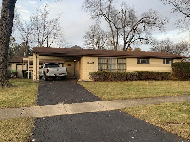 view of front of house featuring driveway, a chimney, an attached carport, and a front yard