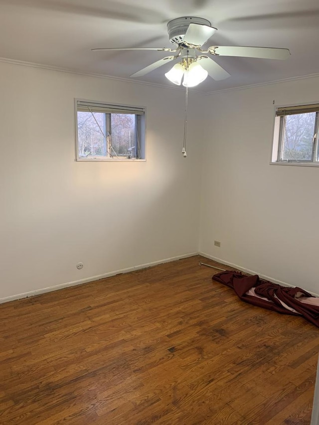 empty room with ornamental molding, a ceiling fan, baseboards, and wood finished floors