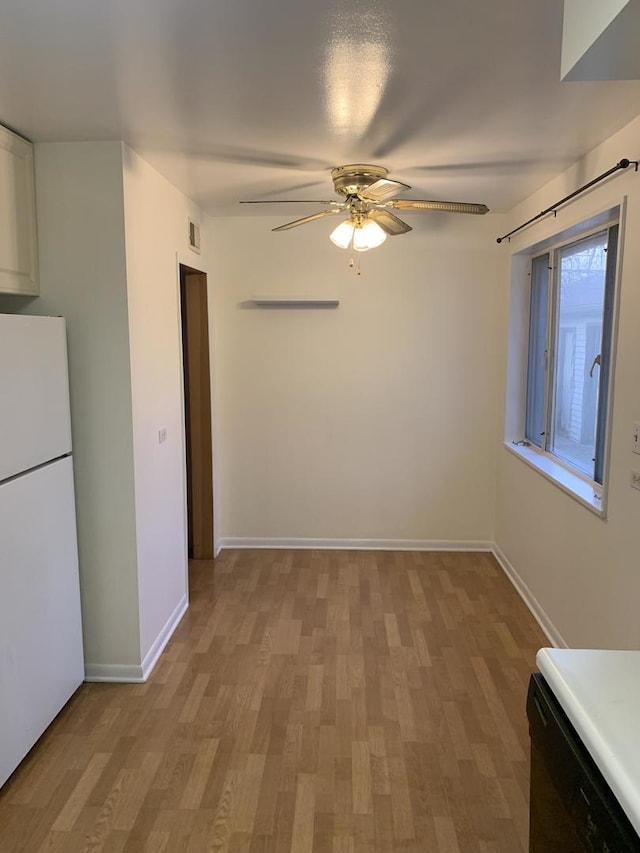 empty room featuring baseboards, light wood-style flooring, visible vents, and a ceiling fan