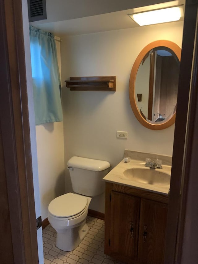 bathroom with baseboards, visible vents, vanity, and toilet