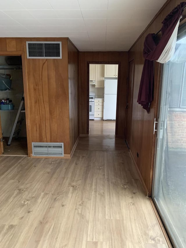 corridor featuring wood walls, visible vents, and light wood-style floors