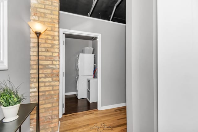 corridor with light wood-style floors, brick wall, and baseboards