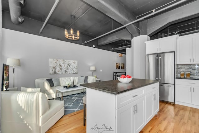 kitchen with light wood finished floors, high quality fridge, open floor plan, a center island, and backsplash