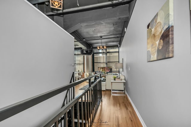 hall featuring an inviting chandelier, baseboards, an upstairs landing, and wood finished floors