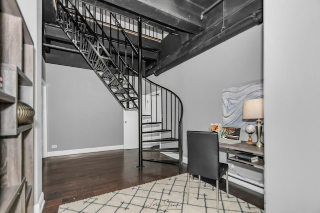 home office with a high ceiling, wood finished floors, and baseboards