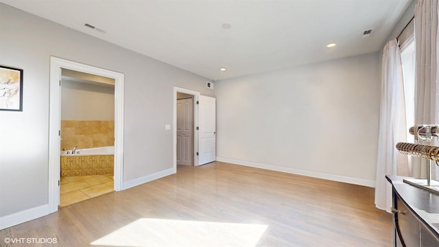 unfurnished bedroom with baseboards, visible vents, ensuite bath, recessed lighting, and light wood-type flooring