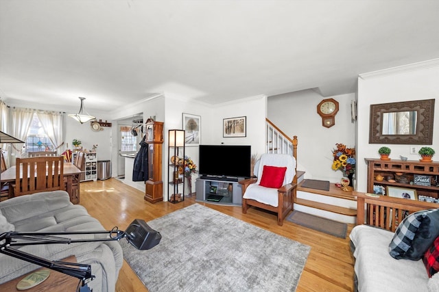 living room with light wood-type flooring, stairway, and ornamental molding