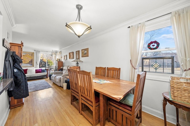 dining room featuring light wood finished floors, ornamental molding, and baseboards