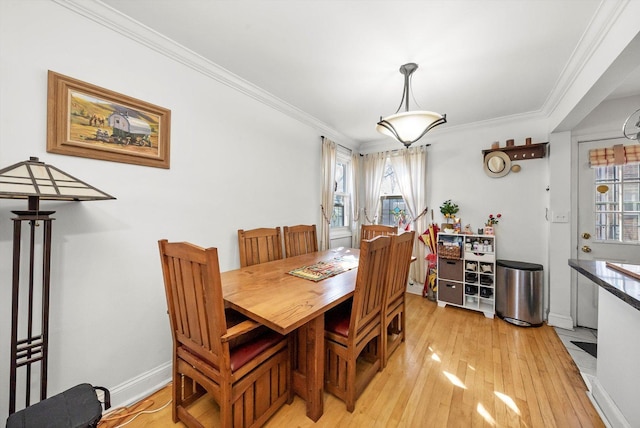 dining room featuring light wood-style floors, crown molding, and baseboards