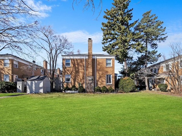 back of property with an outbuilding, a storage shed, brick siding, a yard, and a chimney