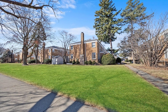 view of side of property featuring a storage shed, brick siding, an outdoor structure, a yard, and a chimney